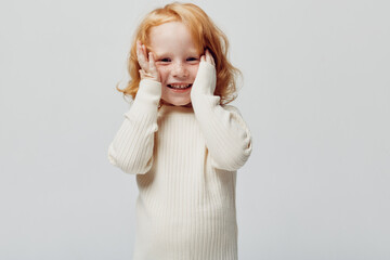 Little girl in white sweater covering her eyes with hands, innocent beauty of childhood gesture,...
