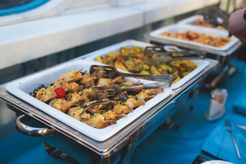Beautifully decorated catering banquet table with different main course hot food dishes and garnish, with rice, chicken, salmon fish, lamb, vegetables and kebab on party event wedding celebration