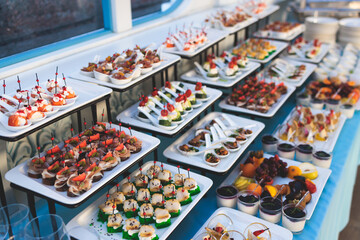 Beautifully decorated luxury banquet catering table, with variety of with different food snacks appetizers on corporate birthday party event wedding celebration, canape, salad, delicatessen variety