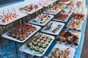 Beautifully decorated luxury banquet catering table, with variety of with different food snacks appetizers on corporate birthday party event wedding celebration, canape, salad, delicatessen variety