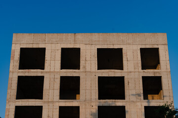 Abandoned building with symmetrical window openings against clear sky