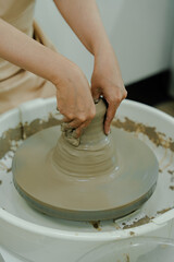 Potter shaping a clay pot on a spinning wheel in a ceramics class