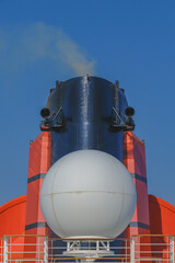 Red and black funnel smoke stack of legendary luxury ocean liner cruise ship against deep blue sky...