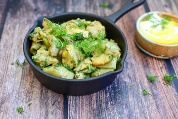 Home made  organic fried zucchini in cast iron pan  with  garlic sauce on wooden background