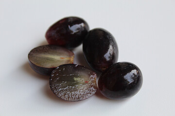 Halved seedless black grape, off the stem, without stalk, isolated on white background