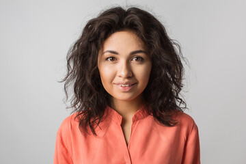 close up portrait of young happy pretty brunette woman in orange shirt, curly hair, brown eyes,...