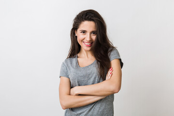 Fototapeta premium portrait of stylish young pretty woman smiling in grey t-shirt on white studio background, isolated, natural look, long brown hair, crossed arms