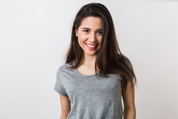 portrait of stylish young pretty woman smiling in grey t-shirt on white studio background, isolated, natural look, long brown hair, sincere smile