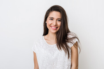 Fototapeta premium portrait of young pretty woman smiling in white t-shirt on white background, happy, positive mood, isolated, sincere smile, long hair