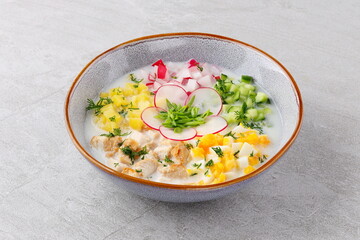 Okroshka smoked chicken breast - Russian cold soup with vegetables on white wooden background. Selective focus