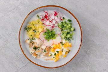 Okroshka smoked chicken breast - Russian cold soup with vegetables on white wooden background. Selective focus