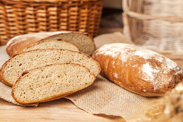 Homemade bread, Whole loaf and sliced on a wooden table against a background of wicker baskets.