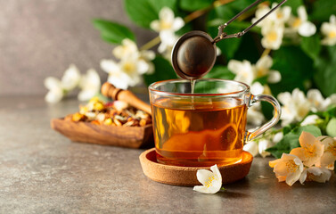 Cup of jasmine tea and fresh jasmine flowers on a stone table.