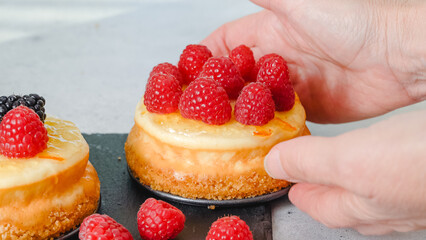Mini cheesecakes close-up. Topping cheesecakes with orange marmalade, fresh berries, and rosemary
