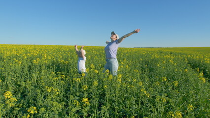 Fototapeta premium Boy And Mother Playing In Canola Field In Summer. Little Cute Boy In A Rapeseed Field Flower. Child Plays In Rape Flower Field.