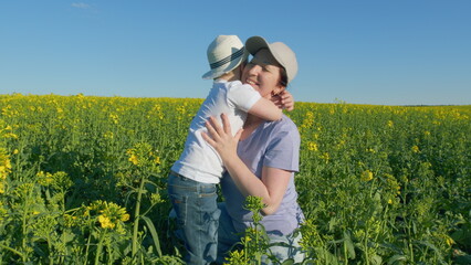 Happy Family Of Farmers Are Playing In A Field Of Rapeseed. Family Lifestyle Mom Takes Care Of Son Childhood. Cheerful Family Relaxing In Nature.