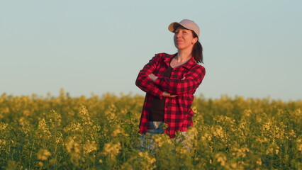 Portrait of pretty young Caucasian woman in cap standing in green field. dressed in a plaid shirt and a black T-shirt. Farming concept harvesting.