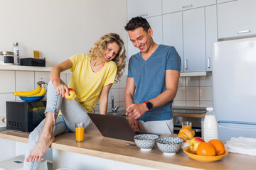 young attractive couple of man and woman cooking breakfast together in morning at kitchen