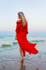 beautiful free woman in red dress in wind on sea beach
