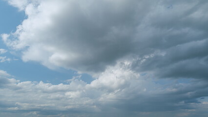 Summer skyscape with dark storm rain clouds on sky. Clouds against a blue sky turning into dark rain cyclones. Timelapse.