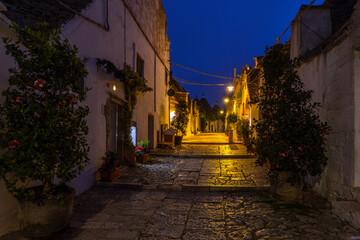 Famous historical old dry stone trulli houses with conical roofs in Alberobello, Italy. Night view