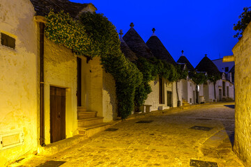 Famous historical old dry stone trulli houses with conical roofs in Alberobello, Italy. Night view