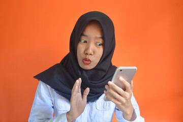 Portrait of an Asian woman with a happy gesture playing with a smartphone in her hand