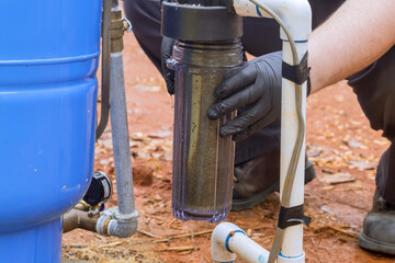 Worker performs maintenance on residential water line filter in domestic water treatment facility