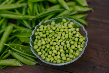 young green peas in pods on wooden background