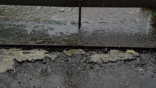 raindrops falling on the concrete floor which is starting to erode with a stretch of rusty old iron pliers.