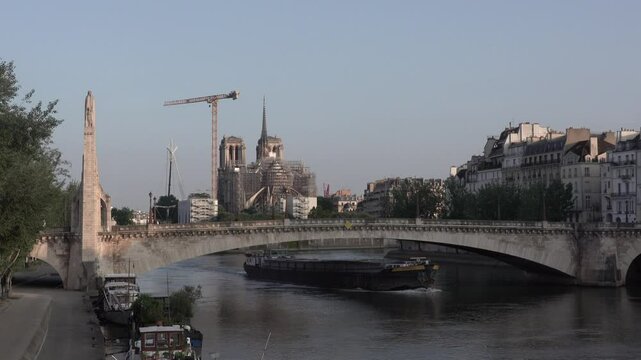 Boat sailing on the Seine River under the Pont de la Tournelle Bridge in Paris, France