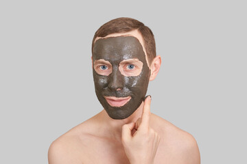 Black Clay Mask on Guy Face. Cosmetology man portrait with mud healthy scrub. Coal nature eco masque. Dermatology charcoal product. Home skin care routine. Skincare male treatment. Applying. Grey