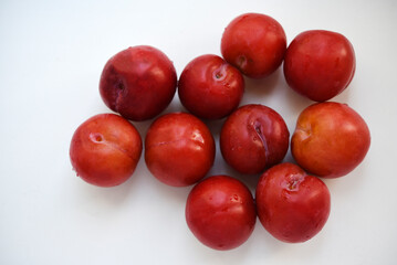 Red plums on a white background.  Plums on a plate. Washed fruits.