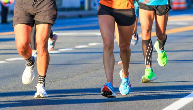 Legs of runners running a race on the roads in bright sunshine