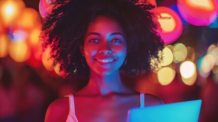A young businesswoman with curly hair is smiling and holding a laptop. The background is vibrant with colorful bokeh lights, creating a lively atmosphere.