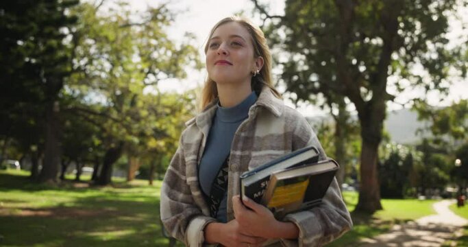 Happy woman, student and walking with books in park for learning, education or path to university. Female person in stroll with textbooks at outdoor campus or college for academic journey in nature