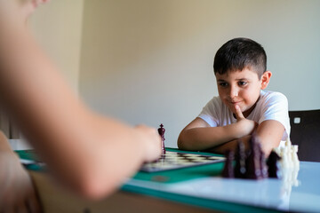 A boy is playing chess with another person