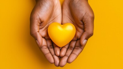 Fototapeta premium Hands holding a yellow resin heart against a matching yellow background, symbolizing mental health awareness and the significance of September Yellow. Mental wellbeing and suicide prevention.