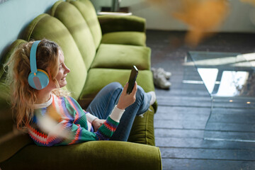 Young woman relaxing with music on cozy sofa