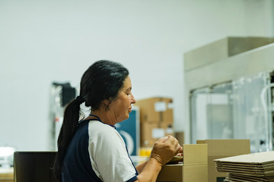 Mature woman packaging products in warehouse