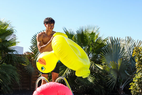 Young man with inflatable duck at poolside