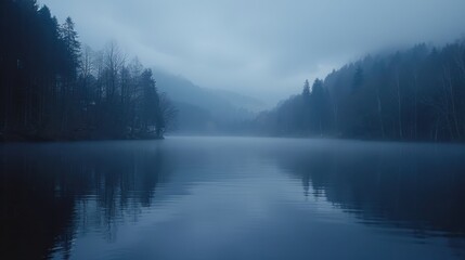 Fototapeta premium A serene lake surrounded by misty trees under a cloudy sky, evoking a calming and atmospheric mood.