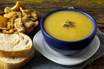 Delicious cassava cream (Caldo ou Creme de Mandioca) or cassava soup, typical of Brazilian cuisine, served in a blue porcelain bowl, on top of a typical rustic farm table, top view with selective focu