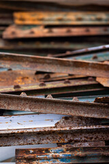 Pile of rusty weathered metal channels in the yard.