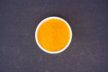 top view of turmeric powder in a white bowl, captured in a close-up shot. isolated in black background