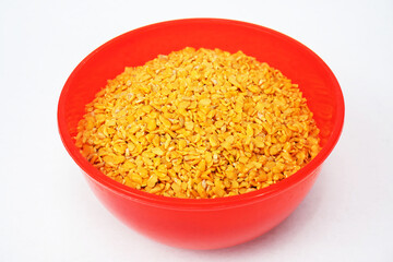 Split mustard seeds, commonly referred to as Rai Kuria, are mustard seeds that have been cracked open. They are frequently used in Indian pickle recipes, in red bowl isolated on white background