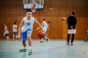 Boy dribbling basketball on court