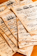 A collection of old papers, handwritten diary sheets covered in intricate handwriting with drawings of sailing ships
