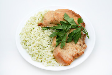 Juicy fried chicken fillet with rice on a plate. Delicious breakfast with meat and rice.