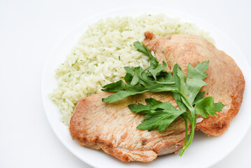 Juicy fried chicken fillet with rice on a plate. Delicious breakfast with meat and rice.